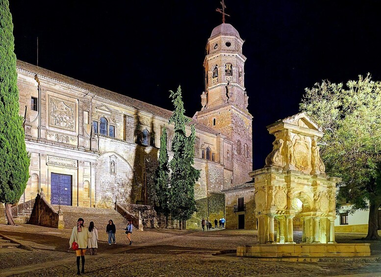 A historic building with a prominent tower, a statue, and a staircase leading to the entrance. 2