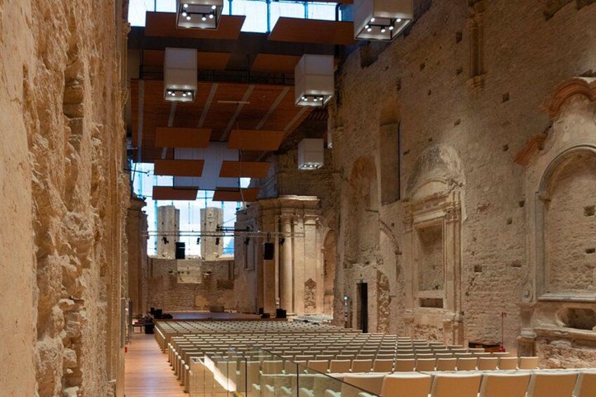 An ancient amphitheater with stone seating and a central stage. 1