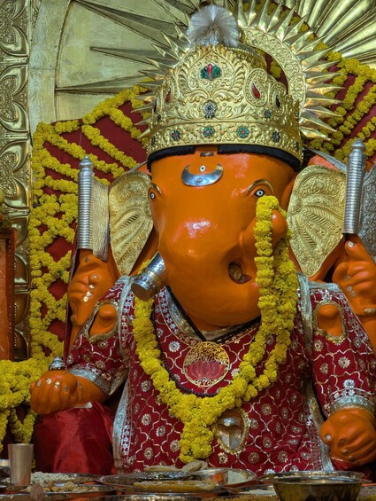 A deity statue adorned with a crown, garlands, and ornate jewelry. 4