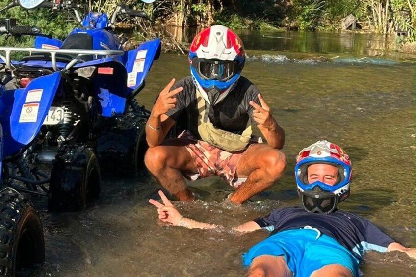 Two people in water with ATVs and a river. 3