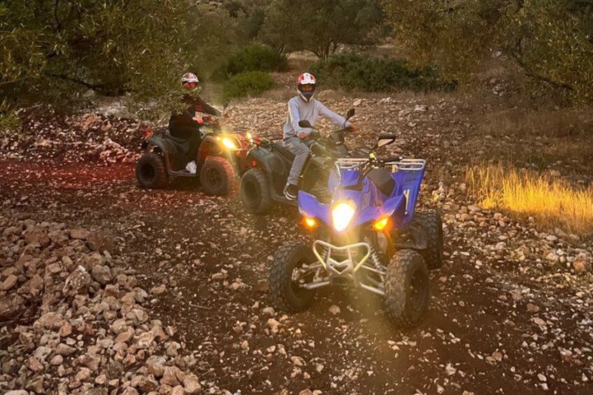 Two people riding ATVs on a rocky trail surrounded by vegetation. 3