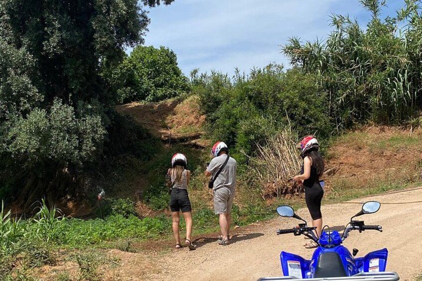 Three people standing on a dirt path with a blue scooter in the foreground. 1