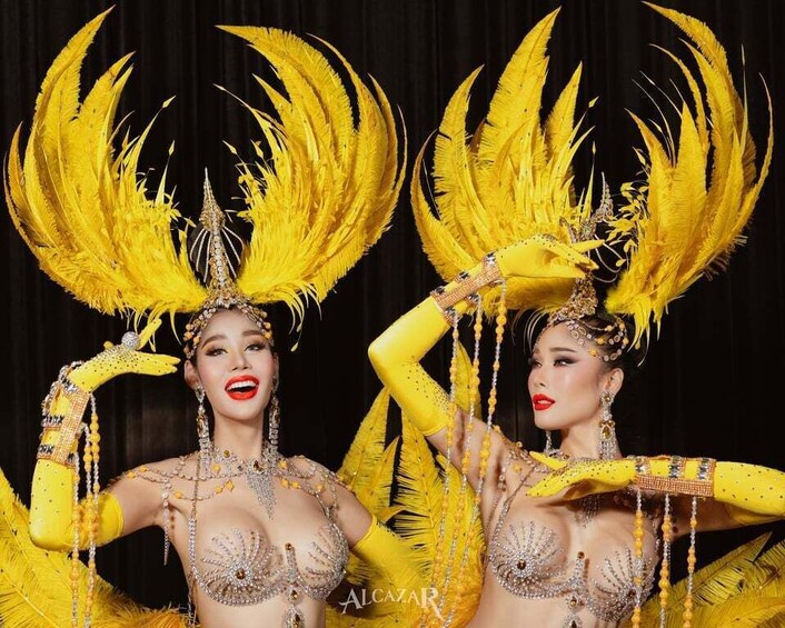 Two individuals in elaborate yellow costumes with feathered headdresses. 1
