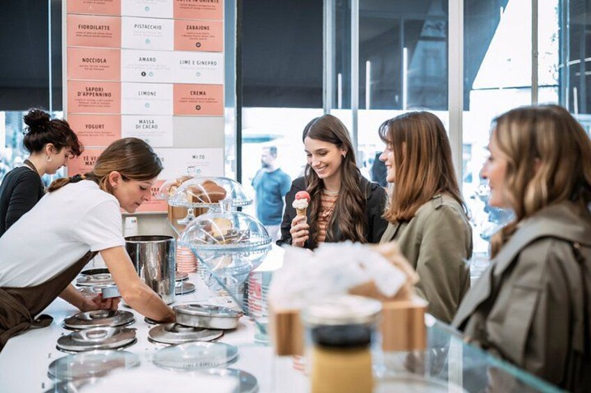 A group of people at a cafe with a menu board in the background listing various food items. 3