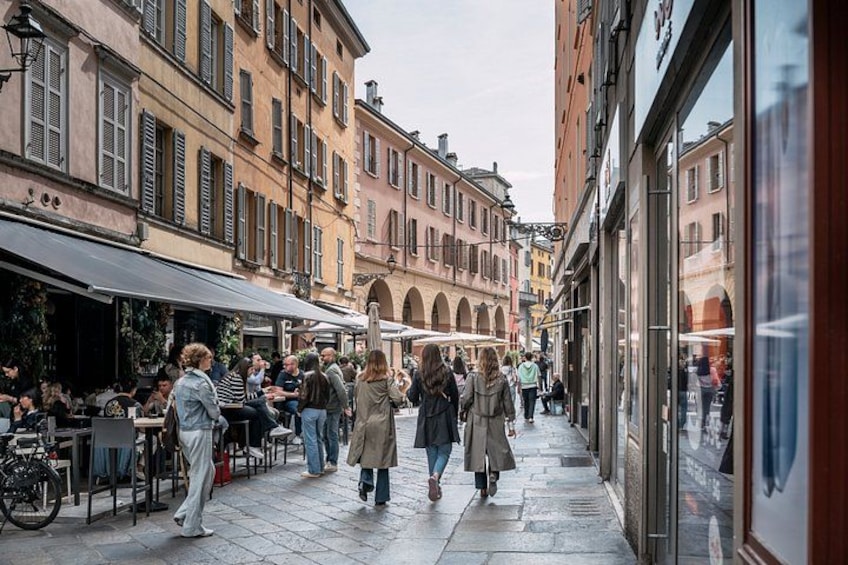 A pedestrian street with cafes, people walking, and historic buildings. 4