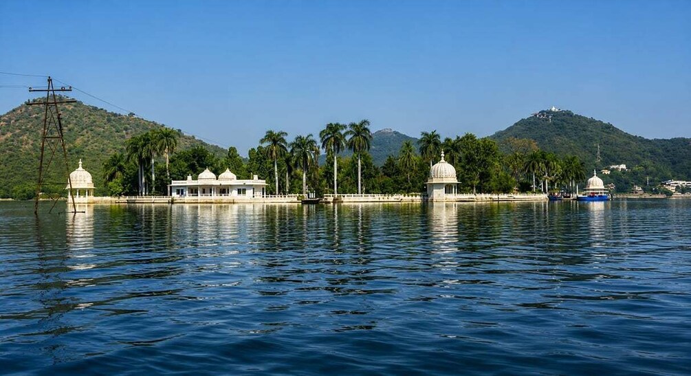 A calm lake with white buildings and palm trees, surrounded by hills. 5