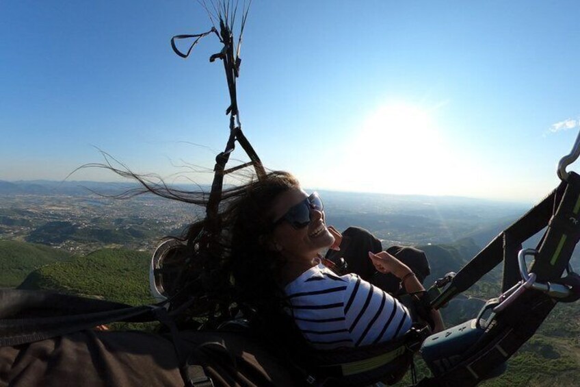A person in a harness, suspended in the air, with a landscape view below. 4