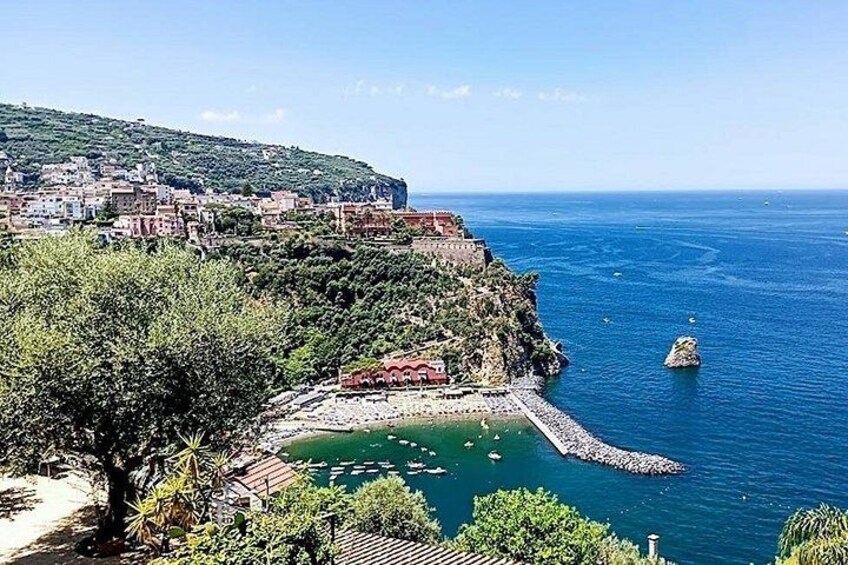 A coastal town with a rocky shoreline, a small bay, and a distant mountain range. 1