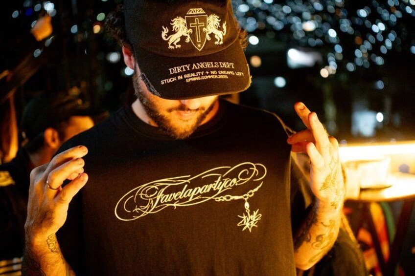 A person wearing a black t-shirt with a crest and a cap with a logo. 5