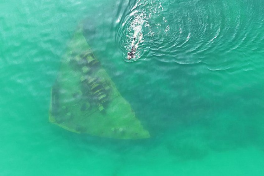 A submerged triangular object with a person in a small boat nearby. 1