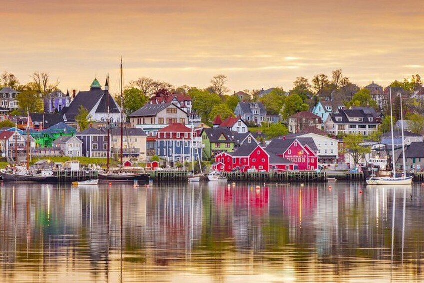 A waterfront town with colorful houses, a calm harbor, and a clear sky. 1