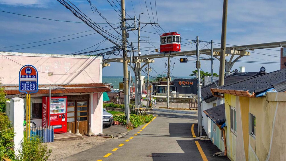 A street with a red tram, a Coca-Cola vending machine, and a signboard. 5