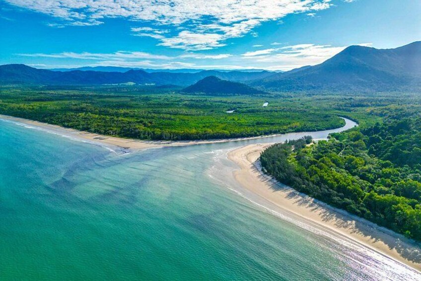 A coastal landscape with a beach, clear waters, and a forested area. 2