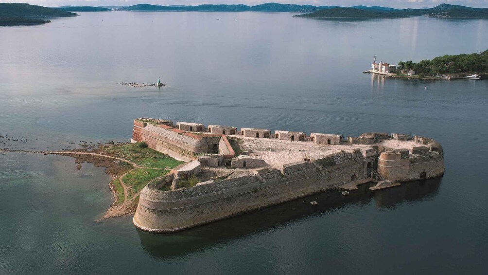 A large medieval fortress on an island surrounded by calm water. 2