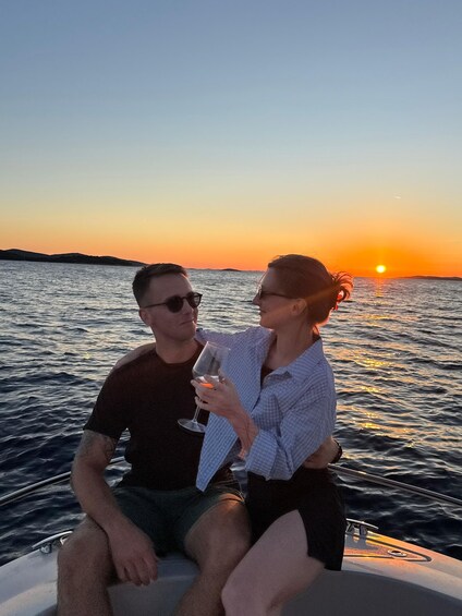 Two people on a boat at sunset with the sun near the horizon. 3