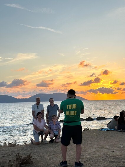 A group of people by a lakeside at sunset with a tour guide. 2