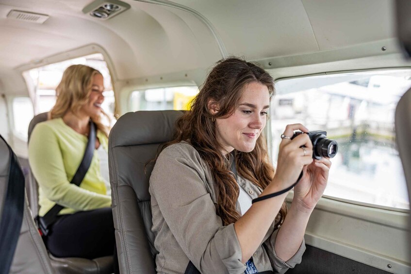 A person taking a photo inside a vehicle with another person seated behind. 5