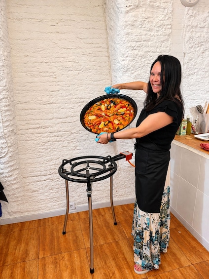 A person cooking seafood paella on a portable stove in a kitchen. 4