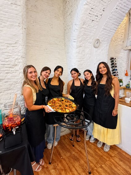 A group of people in a rustic setting with a large seafood platter, white brick walls, and a wine rack. 2
