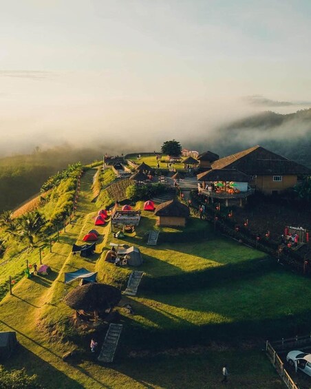 A rural village with houses, tents, and a path leading to a hilltop. 3