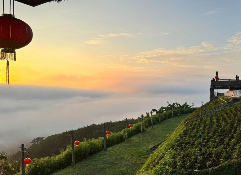 A sunrise over a hilly landscape with red lanterns and a viewing platform. 2