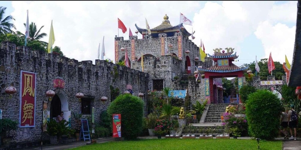 A traditional Chinese building with a stone wall, a pagoda, and various flags. 2