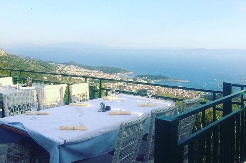 A table set for dining with a view of a coastal town and the sea. 5