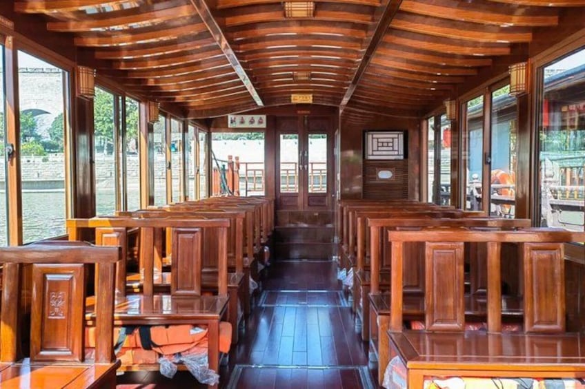 A wooden boat interior with benches and windows overlooking a body of water. 3