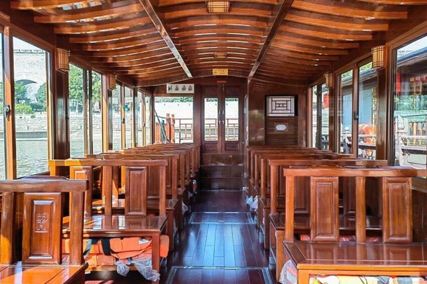 A wooden boat interior with rows of benches and a view of the water outside. 2