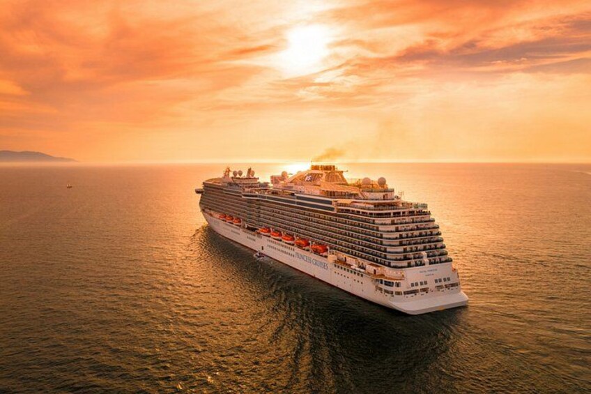 A large cruise ship sailing on the ocean during sunset. 1