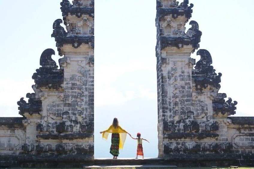 A person standing in front of ancient stone gates with intricate carvings. 1