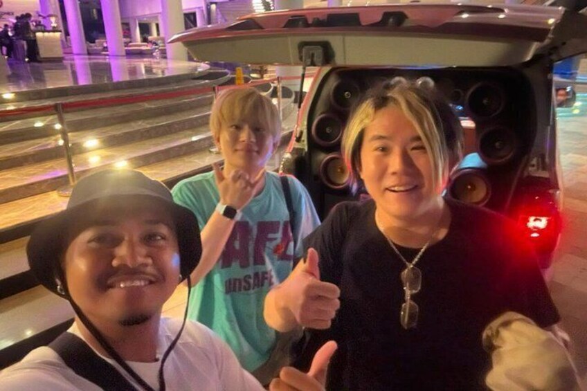 A group of people posing in front of a vehicle with large speakers. 2