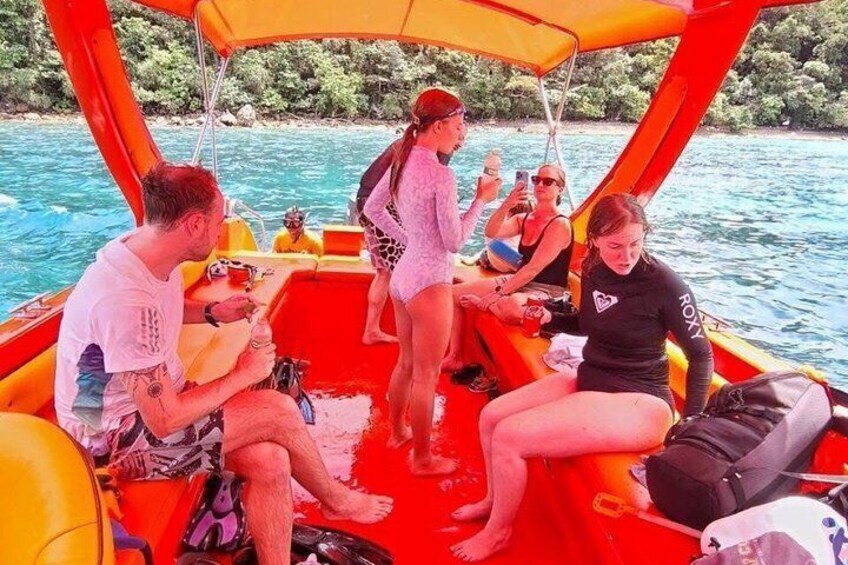 A group of people on a boat with an orange canopy, surrounded by water and greenery. 2