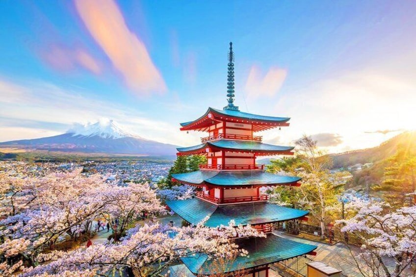 A multi-tiered pagoda with cherry blossoms in the foreground and a snow-capped mountain in the background. 2