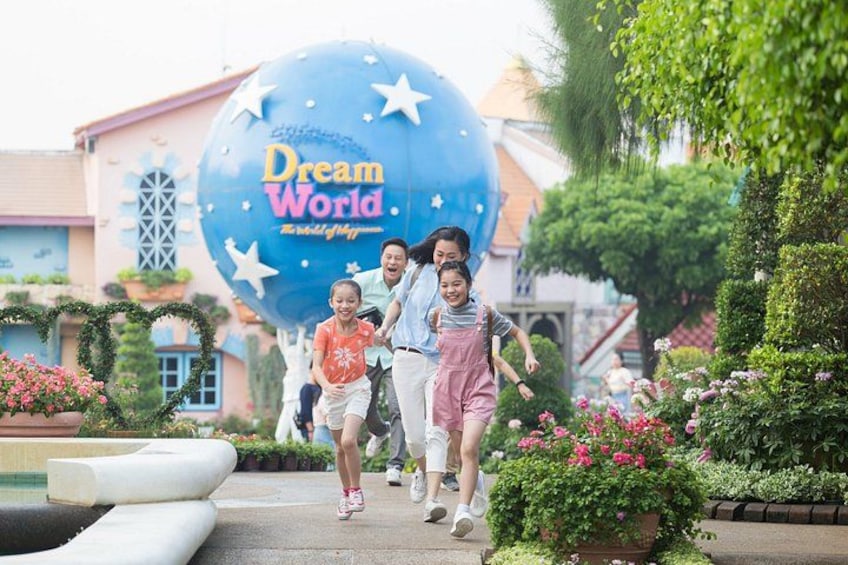 A family walking past a large blue sign with stars and the words 'Dream World.' 2