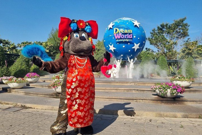A mascot holding a blue fan and a pink fan, with a large blue globe labeled 'Dream World' in the background. 3