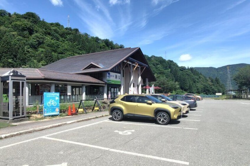 A parking lot with cars, a bus stop, and a building with a sign. 2