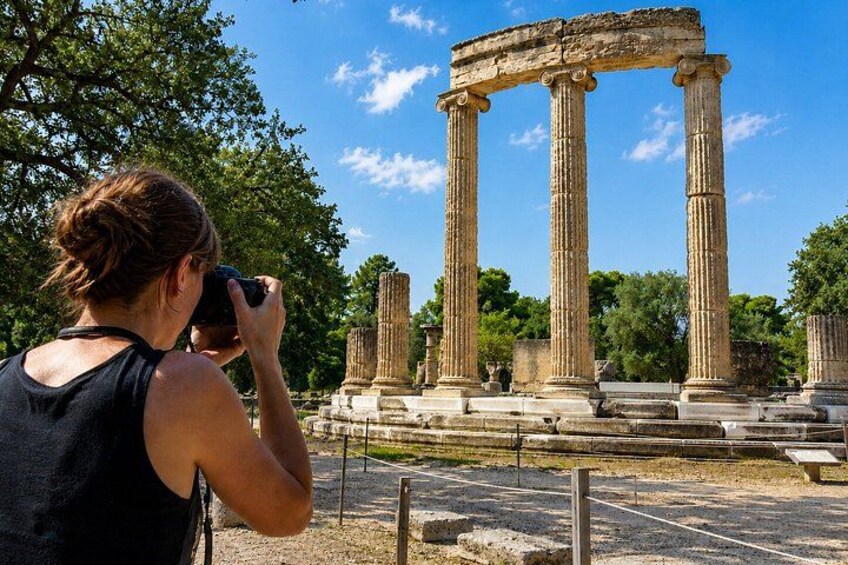 A person taking a photograph of ancient columns. 4