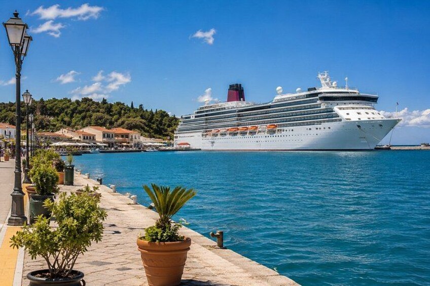A cruise ship docked at a port with a clear blue sky and a coastal town in the background. 2
