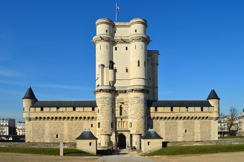 A large castle with two prominent towers, a flag, and a clear blue sky. 4
