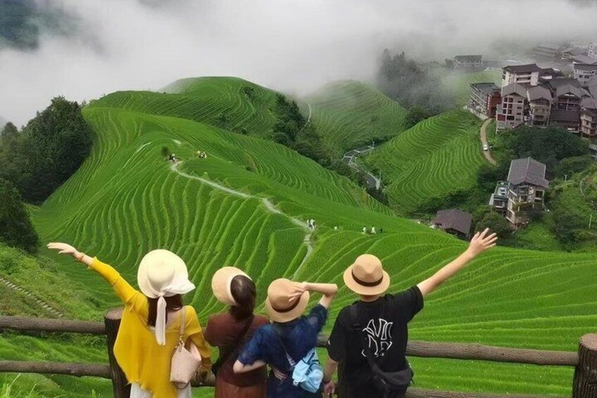 Terraced fields, a wooden fence, and a village in the background. 1