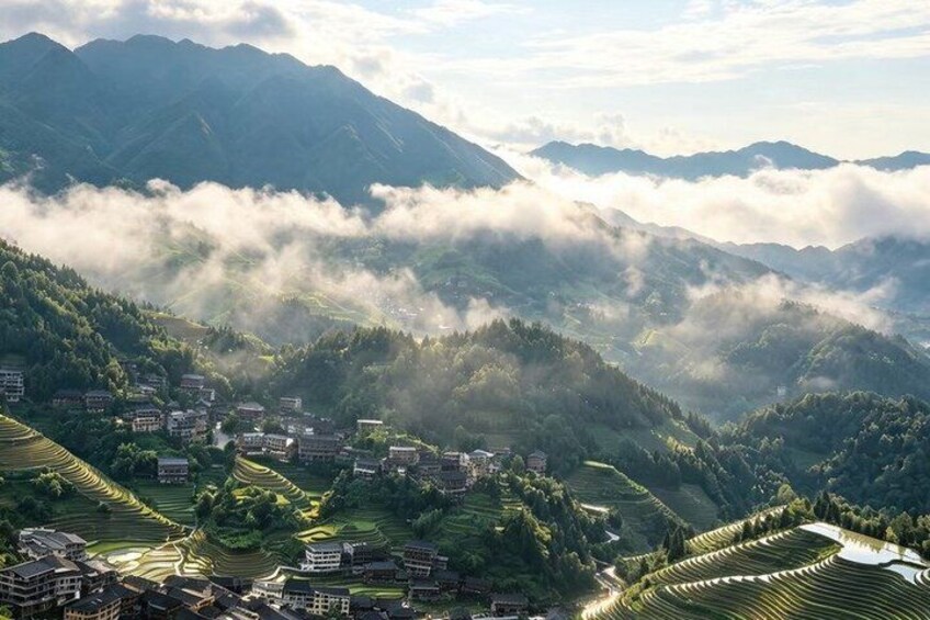 Terraced fields, a village, and mountains with clouds. 2