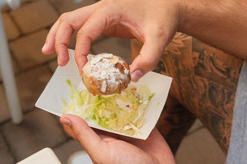A person holding a pastry with powdered sugar and a piece of lettuce. 4