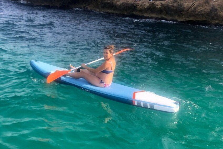 A person sitting on a blue paddleboard in turquoise water. 2