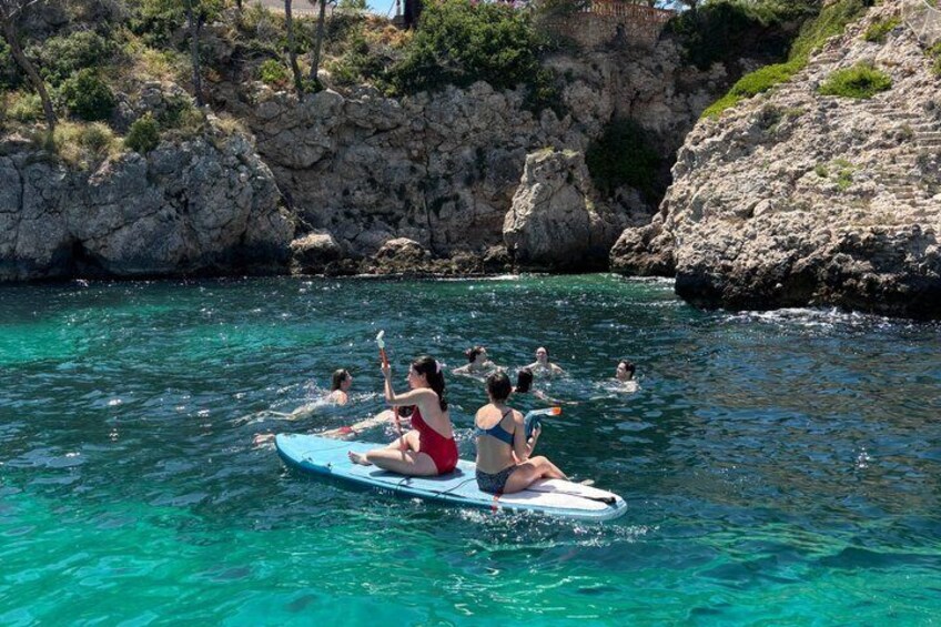People on a blue raft in clear water with rocky cliffs in the background. 4
