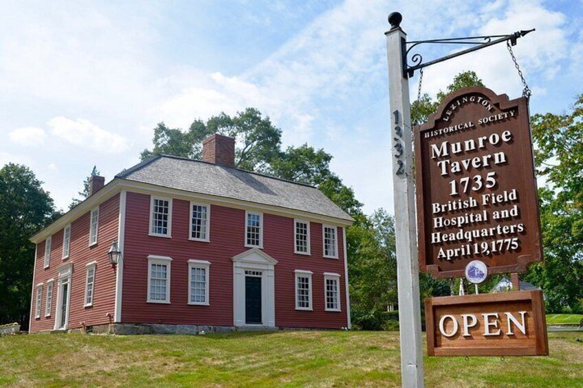 A red colonial building with a sign indicating it is the Munroe Tavern from 1735, located at British Field Hospital and Headquarters. 2