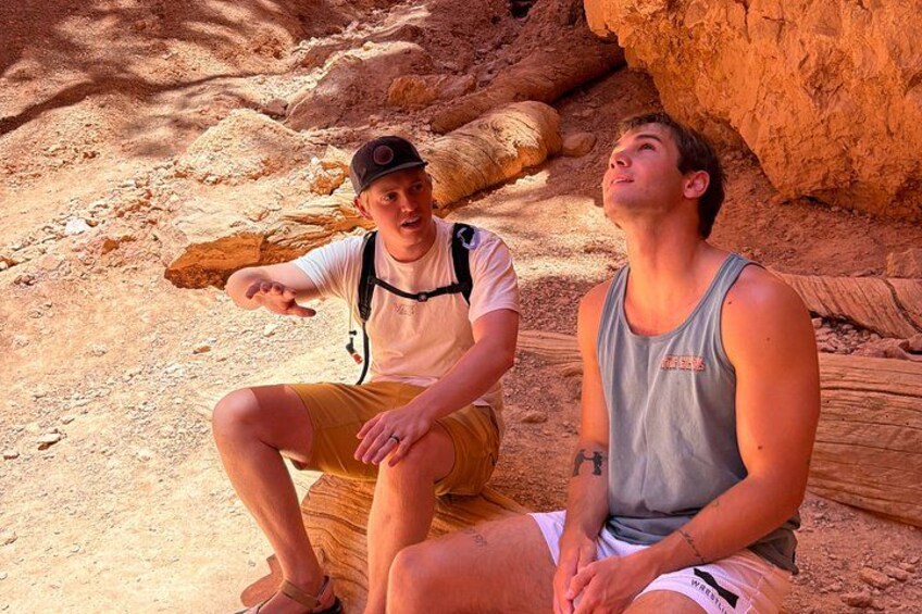 Two people sitting on a rock with a desert landscape in the background. 2