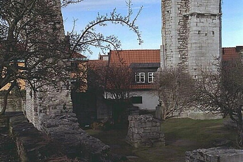 A stone tower, a building with a red roof, and a tree in a courtyard. 2