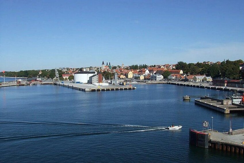 A harbor with calm water, a boat, and buildings in the background. 1