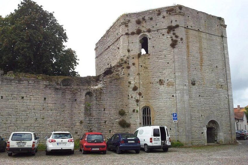 A historic stone tower with a parking area in front. 4